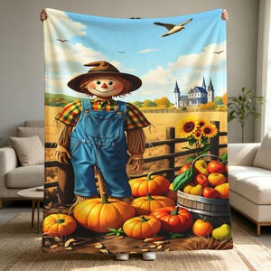 Puede incluir: Una manta de forro polar con un espantapájaros con sombrero marrón y peto azul en un campo de calabazas. La escena incluye girasoles, una valla de madera, una casa grande a lo lejos y un pájaro volando en un cielo azul.