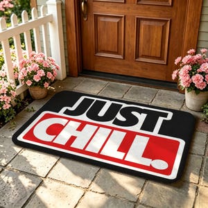 May include: A rectangular black doormat with rounded corners featuring the text JUST CHILL in bold white capital letters. The word CHILL is set against a red rectangular background. The mat is positioned on a stone patio in front of a wooden door.