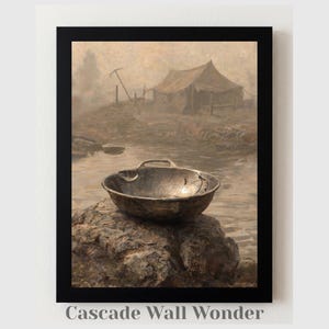 Op de afbeelding: Een ingelijste kunstdruk getiteld Cascade Wall Wonder met een goudkleurige goudpan op een donkere rots. De achtergrond toont een gedempt, sepia-kleurig landschap met een tent en een houweel bij een waterpartij.