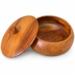 Può includere: Una ciotola rotonda in legno con coperchio circolare abbinato dotato di pomello centrale. La ciotola e il coperchio sono realizzati con segmenti di legno marrone chiaro e medio con venature naturali visibili e una finitura liscia e lucida.