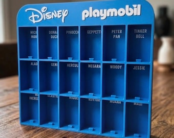 Puede incluir: Un expositor de plástico azul con dieciocho compartimentos rectangulares. La parte superior presenta el texto blanco Disney y playmobil. Cada compartimento está etiquetado con nombres de personajes como Mickey Mouse, Donald Duck, Pinocchio y Peter Pan.