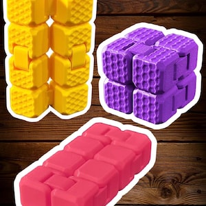 May include: Three articulated fidget toys made of plastic blocks. One is yellow and elongated, one is purple and folded into a cube shape, and one is pink and laid flat. Each block features a textured grid pattern on its outer surface.