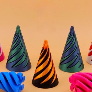 Pode incluir: Uma coleção de objetos em forma de cone com ranhuras em espiral. O conjunto inclui dois cones metálicos verde e azul, um cone listrado laranja e preto, uma peça em espiral azul brilhante, uma peça em espiral rosa choque e cones vermelho e branco.