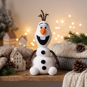 Könnte beinhalten: Eine weiß gehäkelte Schneemannfigur mit einer orangefarbenen, karottenförmigen Nase, einem breiten schwarzen Mund mit einem einzelnen weißen Zahn, zwei schwarzen Augen, drei schwarzen Knöpfen am Rumpf sowie braunen Ärmchen und Haaren.