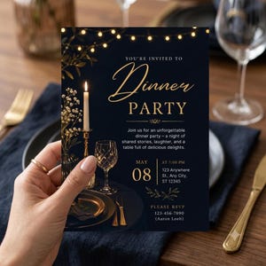 Może przedstawiać: Ciemnoniebieskie zaproszenie na kolację ze złotym tekstem: You're invited to Dinner Party, May 08 at 7:00 PM, 123 Anywhere St., Any City, ST 12345. Projekt zawiera zapaloną świecę, sznur lampek oraz złote zdobienia w kształcie liści.
