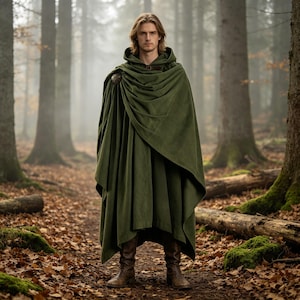 May include: A floor-length olive green hooded cloak featuring a draped fabric design and a circular metallic clasp at the shoulder, worn over brown leather boots. The garment is made of a solid, opaque material with visible folds and a hood.