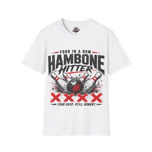 May include: A white short-sleeve t-shirt featuring a graphic print with the text "FOUR IN A ROW HAMBONE HITTER" and "FOUR DEEP. STILL HUNGRY." The design includes a black bowling ball with red claw marks, white bowling pins, and four red X symbols.
