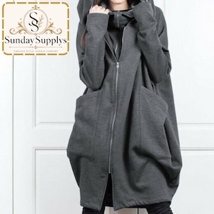 May include: A dark gray hooded jacket featuring a full-length silver zipper, long sleeves, and two large front pockets. The garment has a loose, oversized fit and a high collar. The logo for Sunday Supplys is visible in the top left corner.