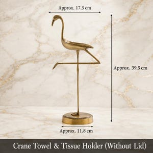 May include: A brass-colored metal crane towel and tissue holder standing on a circular base. The crane is depicted on one leg with a width of approx. 6.89 inches, a height of approx. 15.55 inches, and a base diameter of approx. 4.65 inches.