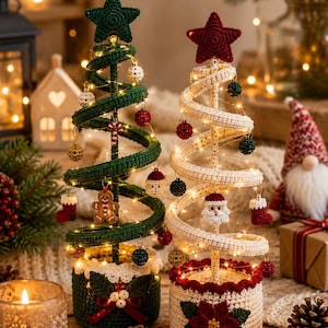 May include: Two spiral Christmas tree decorations made of crocheted yarn. One tree is dark green with a green star topper, the other is cream with a red star topper. Both feature string lights and small crocheted ornaments like stockings and figures.