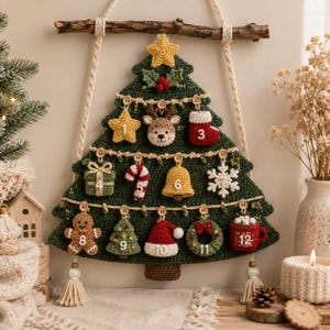 Könnte beinhalten: Ein dunkelgrüner, gehäkelter Weihnachtsbaum als Wandbehang, der an einem Holzast hängt. Er ist mit einem gelben Stern, Stechpalmenblättern und zwölf nummerierten Ornamenten wie einem Rentier, einem Stiefel, einem Geschenk und einem Lebkuchenmann verziert.