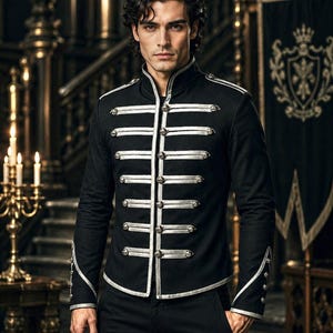 May include: A black military-style jacket featuring a high collar, long sleeves, and silver-toned trim. The front is adorned with horizontal silver piping and metallic buttons arranged in rows, with matching silver trim on the cuffs and hem.
