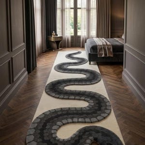 Peut inclure: Un long tapis rectangulaire orné d'un grand motif de serpent sinueux dans des tons de gris anthracite, gris ardoise et noir. Le corps du serpent s'étend sur toute la longueur du tapis crème, avec une tête détaillée et une langue bifide.