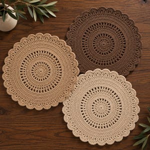 May include: Three circular crochet doilies in varying shades of brown, tan, and cream. Each doily features a central radial pattern, concentric rings of openwork stitches, and a decorative scalloped edge finish around the entire circumference.