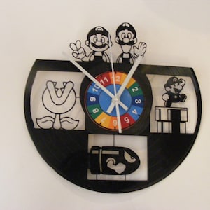 May include: A black vinyl record clock featuring a colorful clock face with numbers 1-12, and four black and white images of characters from the Super Mario Bros. video game. The images include a Piranha Plant, a Goomba, a Koopa Troopa, and two Mario characters.