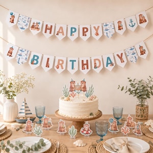 Könnte beinhalten: Ein Happy Birthday Banner mit Aquarell-Ottern, Ankern und Leuchttürmen sowie passenden Tortensteckern auf einer Torte. Das Party-Set enthält kleine Otter-Aufsteller, einen hölzernen Tortenständer und nautische Illustrationen.