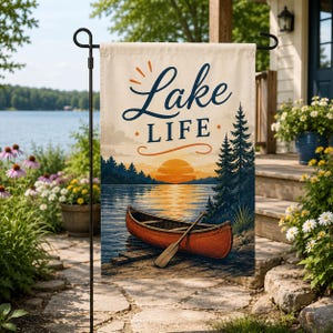 May include: A rectangular garden flag featuring a sunset over a lake with a red canoe and a wooden paddle in the foreground. The text Lake LIFE is printed in dark blue script and block letters at the top against a cream-colored background.
