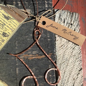 May include: A copper wire music note ornament with a brown paper tag that says "Jane McLroy".