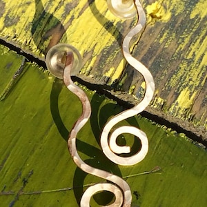 May include: A pair of gold-toned earrings with a hammered finish. Each earring features a wavy design with a spiral at the end.