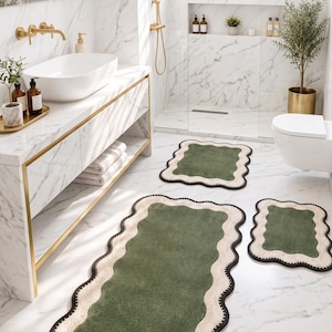 May include: A set of three rectangular bath mats featuring a textured dark green centre, a wide cream-coloured scalloped border, and a thin black outer edge. The text at the bottom reads THE VERDANT COLLECTION • CURATED FOR ARCHITECTURAL DIGEST.