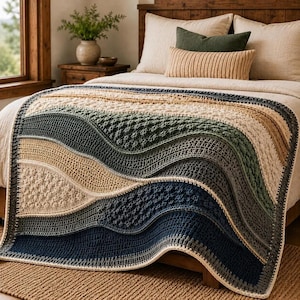 Op de afbeelding: Een rechthoekige gehaakte deken met golvende, horizontale kleurstroken in crème, beige, saliegroen en donker marineblauw. Het ontwerp bevat diverse gestructureerde steken, waaronder noppen en dichte rijen, wat zorgt voor een gelaagd effect.