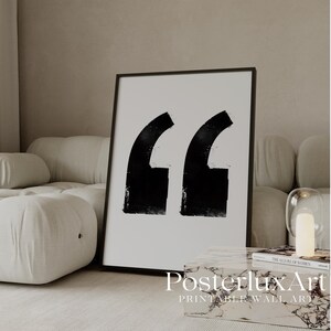 May include: A framed wall art print featuring two large, bold black quotation marks centered on a white background. The artwork is enclosed in a thin black frame, showcasing a high-contrast graphic design with textured, brush-stroke style edges.