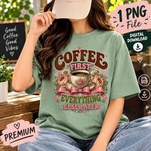 May include: A sage green t-shirt featuring a graphic print of a teacup surrounded by pink flowers and a pink ribbon. The text reads COFFEE FIRST, EVERYTHING ELSE LATER in brown and green lettering, accented with small pink hearts and stars.