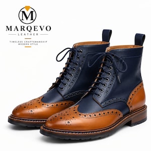 Könnte beinhalten: Ein Paar Schnürstiefel aus marineblauem und hellbraunem Leder im Brogue-Stil mit Flügelkappe, dekorativen Perforationen, Schnürsenkeln und Zuglaschen. Das Logo MARQEVO LEATHER TIMELESS CRAFTSMANSHIP MODERN STYLE ist oben links zu sehen.