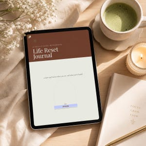 May include: A digital tablet displaying a workbook titled Life Reset Journal, A Self-Guided Workbook, with the subtitle a clear-eyed look at where you are, and where you're headed, and a name tag field containing the name Amelia.