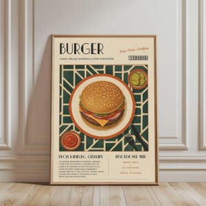 Op de afbeelding: Een rechthoekige wandkunstprint met de titel BURGER, met een centrale illustratie van een burger op een broodje met sesamzaad op een bord, een klein kommetje augurken en een kommetje rode saus. De poster bevat tekst over de geschiedenis en serveertips.