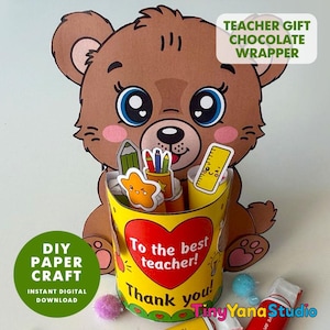 May include: A brown bear paper craft holder featuring a yellow cylindrical container with a red heart and the text To the best teacher! Thank you!. The container holds paper cutouts of a green pencil, a pencil cup, and a yellow ruler.