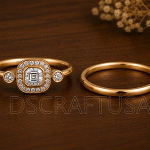 May include: A gold ring set featuring a central square-cut stone surrounded by a halo of small round stones, flanked by two smaller round stones on the band, accompanied by a plain gold band. The text DSCRAFTUSA is visible in the foreground.