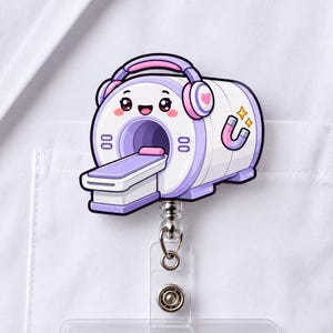 May include: A badge reel featuring a cartoon MRI machine with a smiling face, wearing pink and purple headphones. The machine is white and purple with a small magnet icon and two yellow stars on the side, attached to a clear plastic clip.