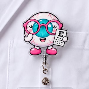 Könnte beinhalten: Ein Ausweishalter mit einer Cartoon-Augapfel-Figur mit leuchtend blauer Iris, die eine rosa Brille trägt und eine weiße Sehtafel mit dem Buchstaben E hält. Die Figur hat rosa Schuhe und ist an einem durchsichtigen, einziehbaren Mechanismus befestigt.