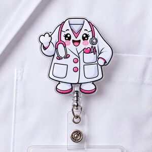 May include: A badge reel featuring a cartoon character wearing a white lab coat and a pink stethoscope. The character has a smiling face, pink cheeks, and a pocket containing a pink heart and two pens. The design is rendered in white, pink, and black.