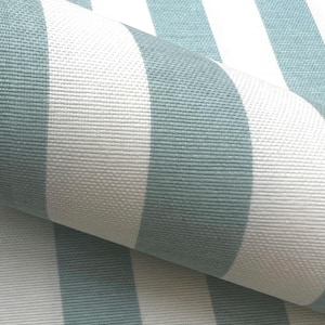 Peut inclure: Un rouleau de tissu présentant un motif répétitif de rayures verticales alternant entre des tons de vert sauge doux et de blanc éclatant. Le textile présente une texture tissée visible avec un motif de tissage en grille cohérent.