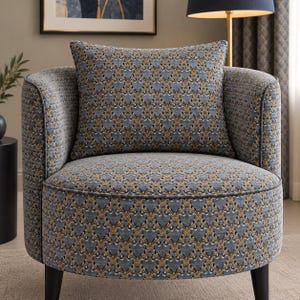 Könnte beinhalten: Ein tonnenförmiger Sessel, bezogen mit einem blau-goldenen Damaststoff. Der Sessel verfügt über eine abgerundete Rückenlehne, ein dickes Sitzkissen und ein passendes quadratisches Zierkissen, getragen von vier dunklen, konischen Holzbeinen.