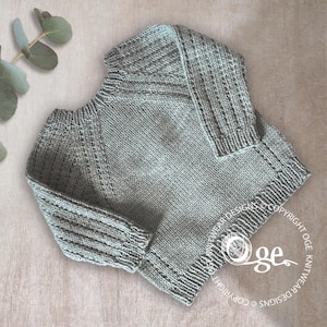 May include: A light gray knitted sweater with a ribbed texture. The sweater has a round neckline and long sleeves.