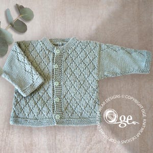 May include: A light green knitted baby cardigan with a diamond pattern and button closure.