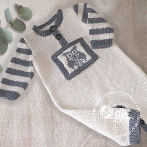 May include: A long-sleeved knit romper in cream and gray. The garment features gray striped sleeves, a gray ribbed neckline with two dark buttons, and a square patch on the chest displaying a gray owl graphic. The leg cuffs are also gray.