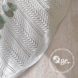 May include: A white crocheted baby blanket with a delicate lace pattern. The blanket is made with a soft yarn and has a scalloped edge.