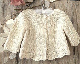 May include: A cream-colored knitted cardigan with a button closure and a scalloped hem.