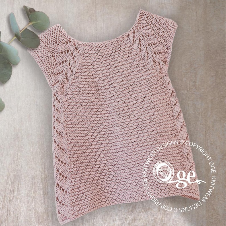 May include: A pale pink knitted baby top with a delicate lace pattern around the neckline and sleeves. The top is made with a fine yarn and has a soft, comfortable feel.