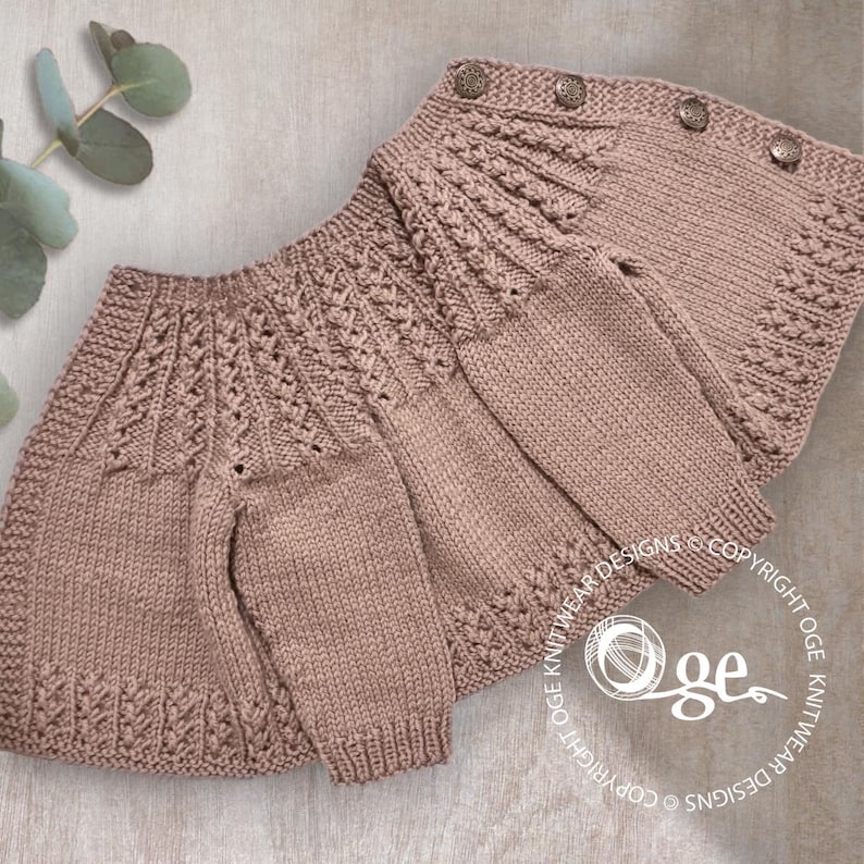 May include: A knitted baby cardigan in a light pink color with a delicate cable stitch pattern. The cardigan has a button closure and is laid flat on a textured surface.