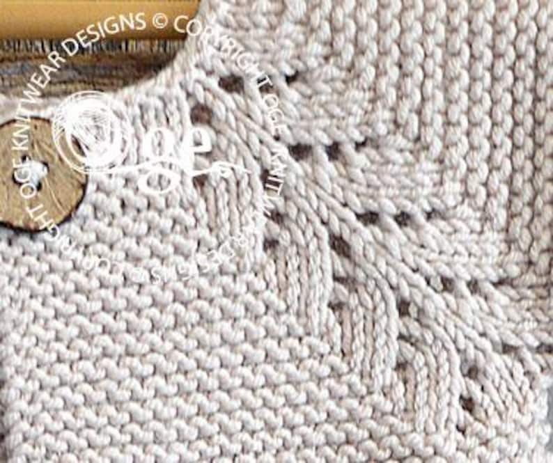May include: Close-up of a beige knitted fabric with a delicate lace pattern at the neckline. The fabric is soft and textured, with a subtle sheen.