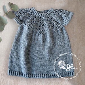 Peut inclure: Une robe en tricot gris pour bébé avec un motif de dentelle autour de l'encolure et des manches courtes. La robe a un design simple et classique.