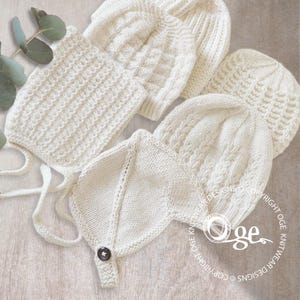 May include: Four white knitted baby hats, one with a button, on a wooden surface. The hats are made with different stitch patterns.