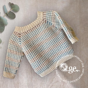 May include: A beige, brown, and blue striped knitted baby sweater with a wide neckline. The sweater is made with a textured stitch pattern.