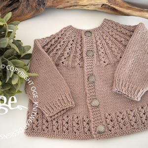 May include: A light brown knitted cardigan with a button closure and a delicate lace pattern around the neckline and hem.