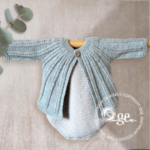 May include: A light blue knitted cardigan with long sleeves and a single wooden button fastening at the neckline. The garment features a textured ribbed pattern radiating from the centre, paired with a solid light blue knitted romper underneath.
